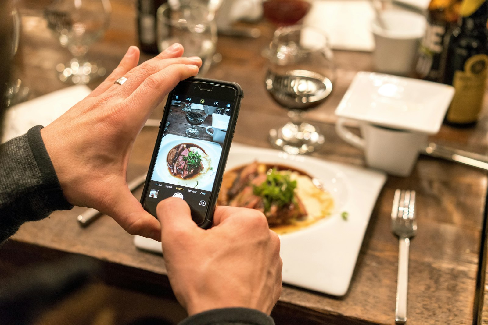 A person photographing a plated meal with their phone